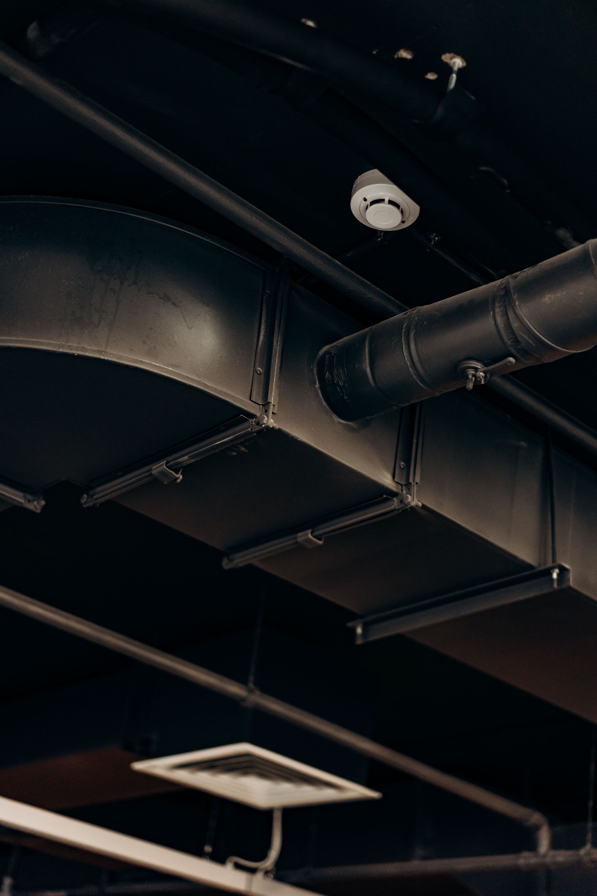 Detailed view of industrial air ducts on a ceiling, showcasing modern urban design.